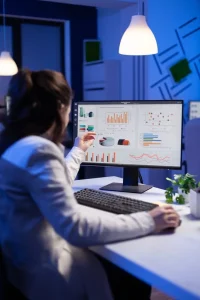 imgi_25_back-shot-overwhelmed-woman-working-night-front-computer-writing-notes-notebook-annual-reports-checking-financial-deadline-focused-manager-using-technology-n